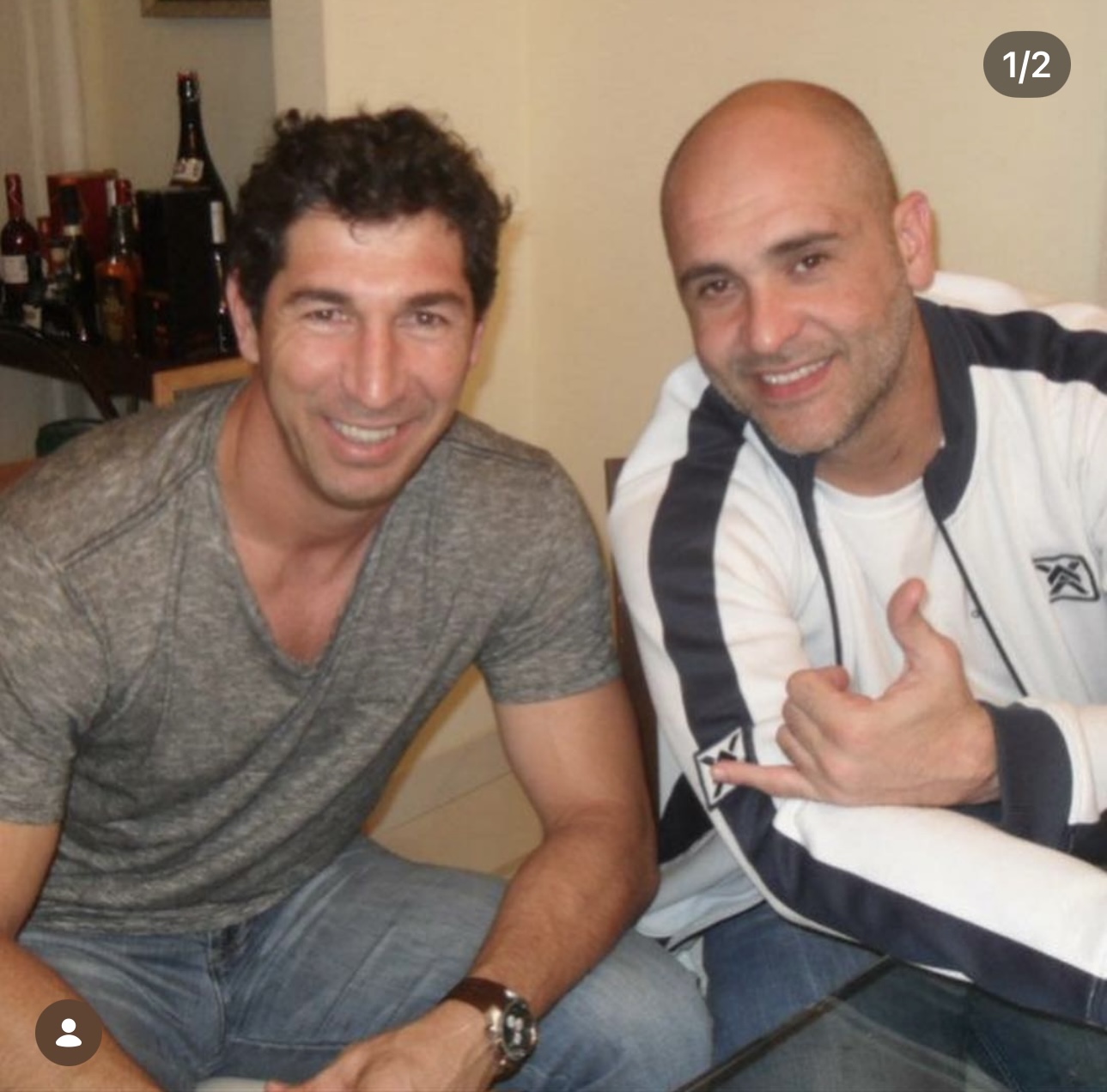 Sérgio e Marcos sorrindo lado a lado em casa, Marcos fazendo o sinal de hang loose